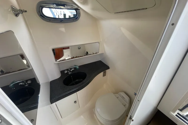 Slide: The Image of 2004 Boston Whaler 305 Conquest boat bathroom with sink, mirror, and toilet. - 24