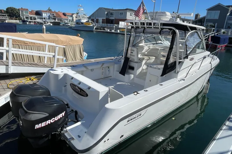 Slide: The Image of 2004 Boston Whaler 305 Conquest boat docked, featuring twin Mercury engines. - 34