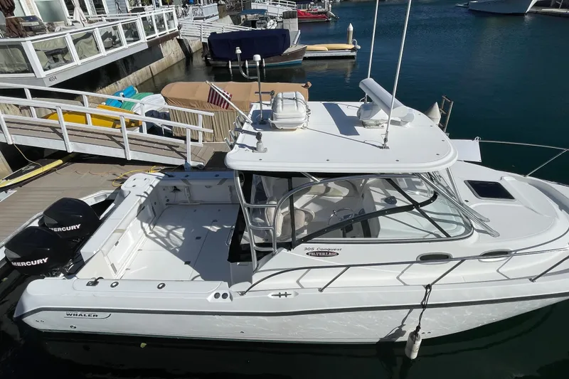 Slide: The Image of 2004 Boston Whaler 305 Conquest boat docked at marina with twin Mercury engines. - 35