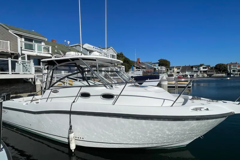 Slide: The Image of 2004 Boston Whaler 305 Conquest boat docked in a marina under clear blue skies. - 37