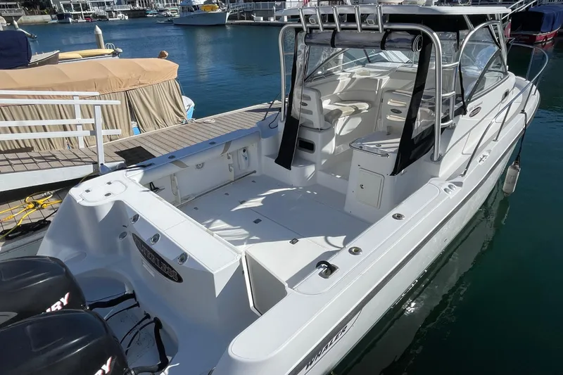 Slide: The Image of 2004 Boston Whaler 305 Conquest boat docked at marina, featuring spacious deck and seating. - 43