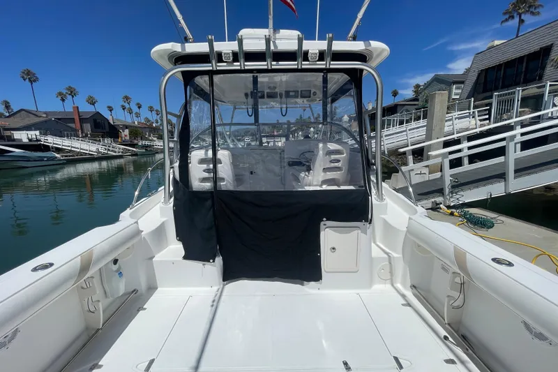 Slide: The Image of 2004 Boston Whaler 305 Conquest boat docked, featuring spacious deck and clear canopy. - 5