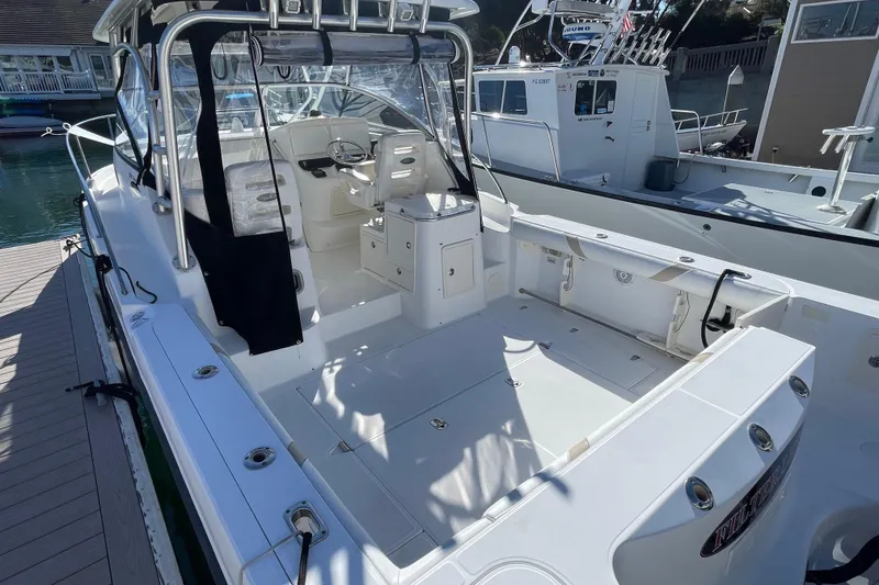 Slide: The Image of 2004 Boston Whaler 305 Conquest boat docked, showcasing spacious deck and seating area. - 54