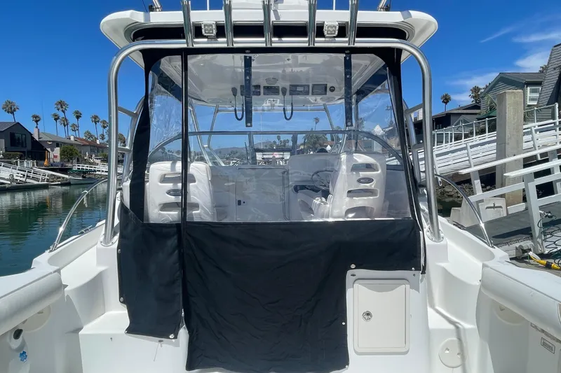 Slide: The Image of 2004 Boston Whaler 305 Conquest boat docked, featuring a covered cockpit and clear skies. - 6
