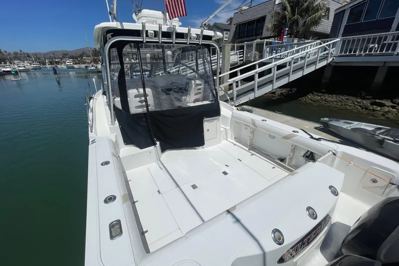 Slide: The Image of 2004 Boston Whaler 305 Conquest boat docked at marina, showcasing spacious deck area. - 7