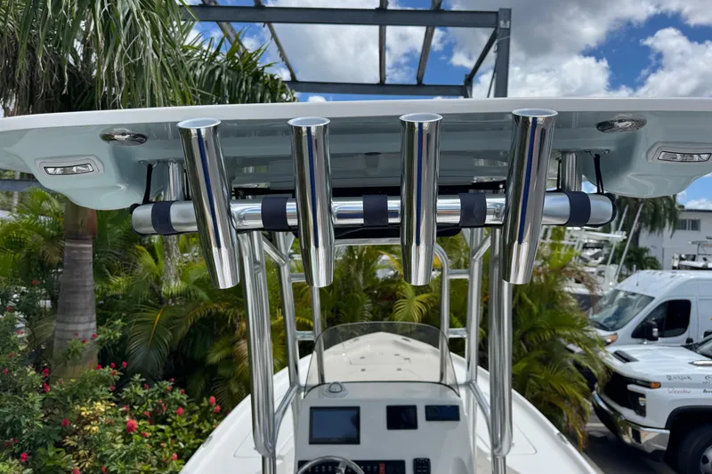 Slide: The Image of 2025 Key West 230 Bay Reef boat with rod holders and console, surrounded by tropical plants. - 10