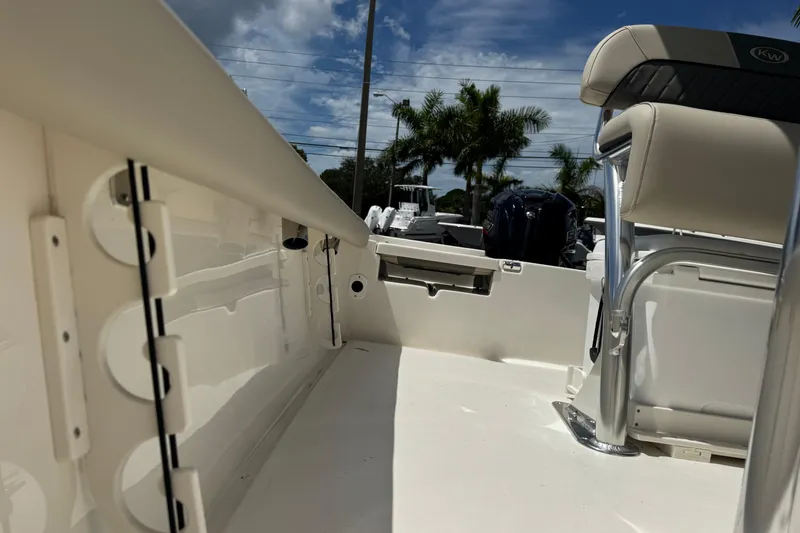 Slide: The Image of 2025 Key West 230 Bay Reef boat interior with seating and storage, under a partly cloudy sky. - 25