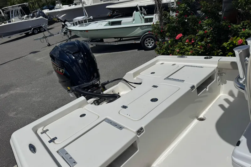 Slide: The Image of 2025 Key West 230 Bay Reef boat with outboard motor, parked near greenery. - 27