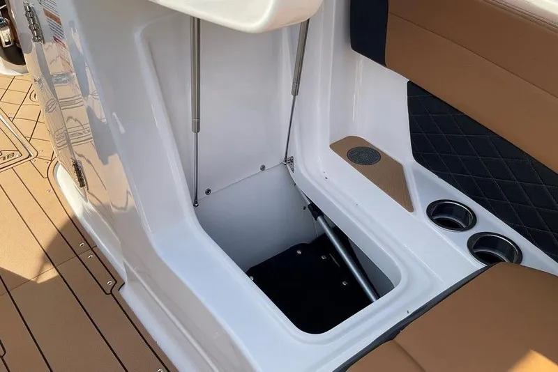 Slide: The Image of 2026 Chaparral SSX 276 boat interior storage compartment with cup holders and cushioned seating. - 41