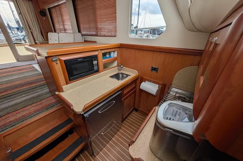 Slide: The Image of 2008 Mainship 38 yacht interior with kitchenette, featuring microwave, sink, and compact appliances. - 17