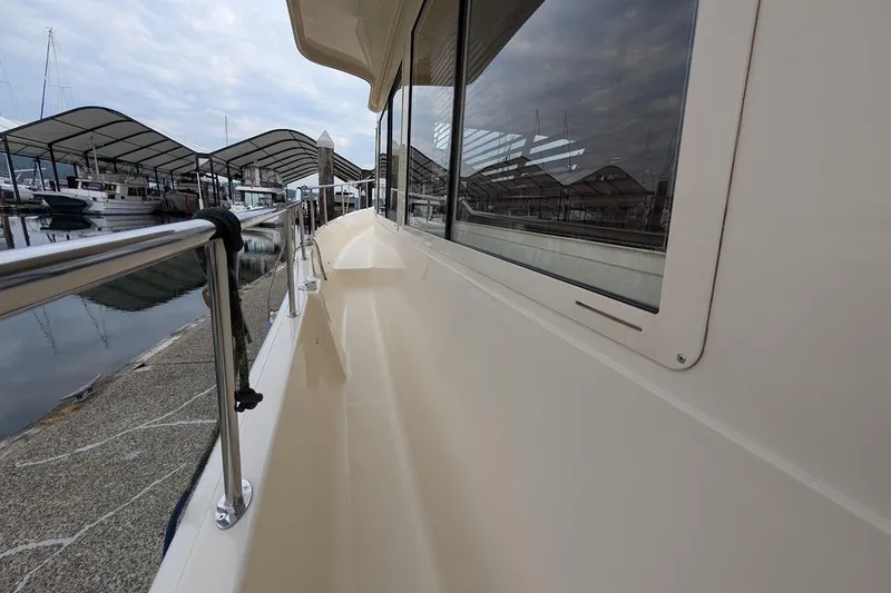 Slide: The Image of 2008 Mainship 38 yacht docked at marina, showcasing sleek side deck and railing. - 6