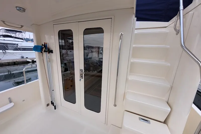 Slide: The Image of 2008 Mainship 38 yacht interior with glass doors and staircase, docked at marina. - 10