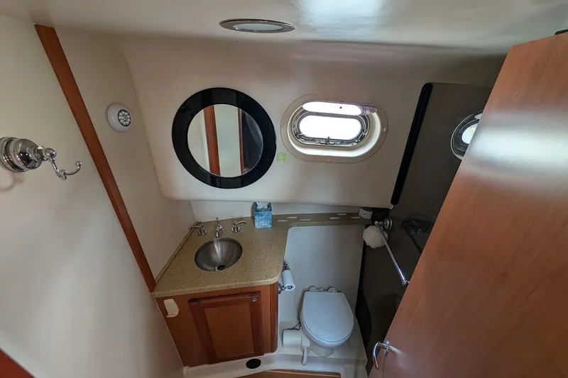 Slide: The Image of 2008 Mainship 38 yacht bathroom with sink, toilet, mirror, and porthole window. - 21