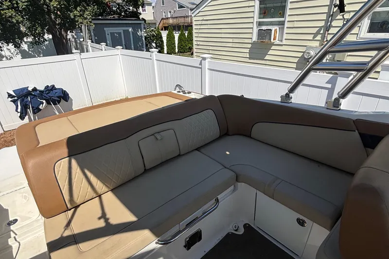 Slide: The Image of 2015 Sea Ray 240 Sundeck interior with beige seating, white fence background. - 10