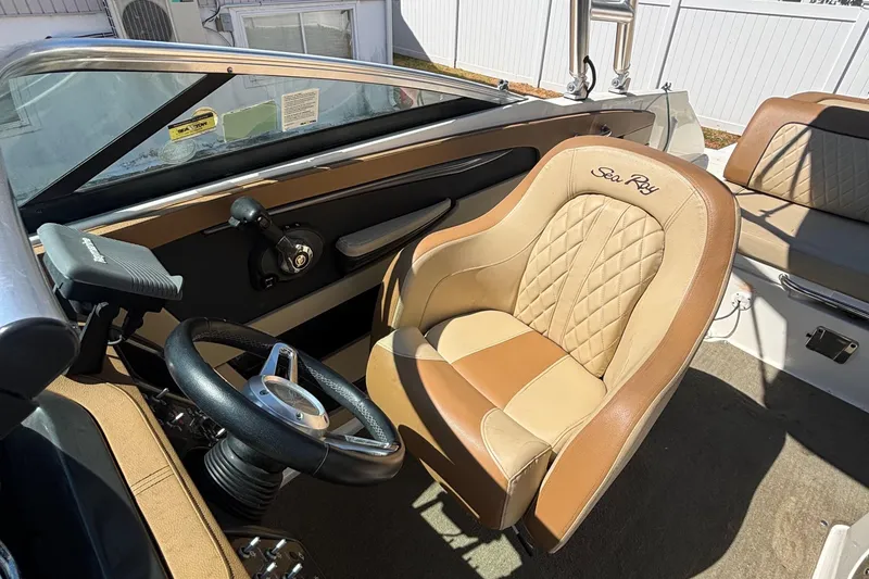 Slide: The Image of 2015 Sea Ray 240 Sundeck interior with tan leather seating and steering wheel. - 14