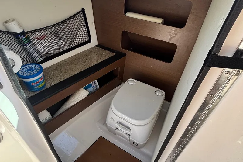 Slide: The Image of Interior of 2015 Sea Ray 240 Sundeck boat with compact toilet and storage shelves. - 26