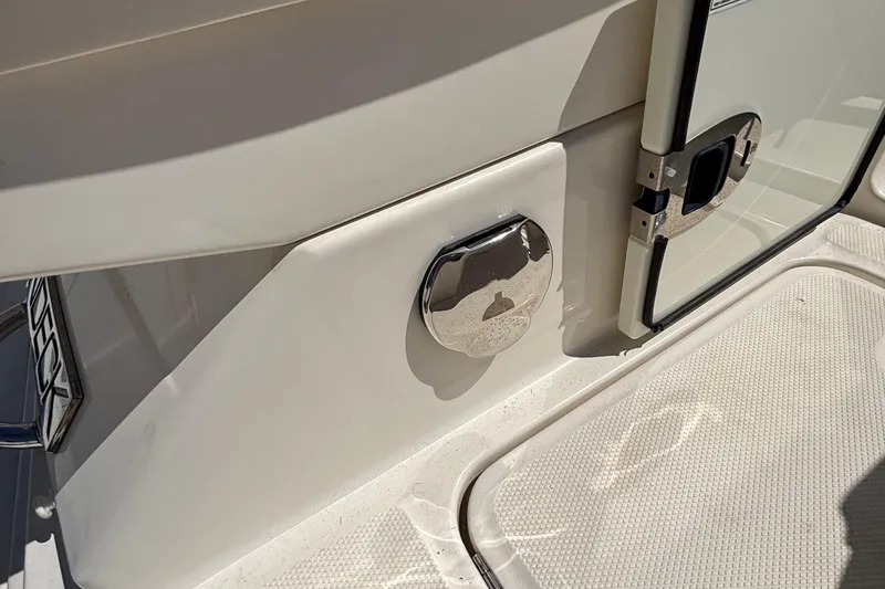 Slide: The Image of 2015 Sea Ray 240 Sundeck boat deck with chrome details and storage compartment. - 32