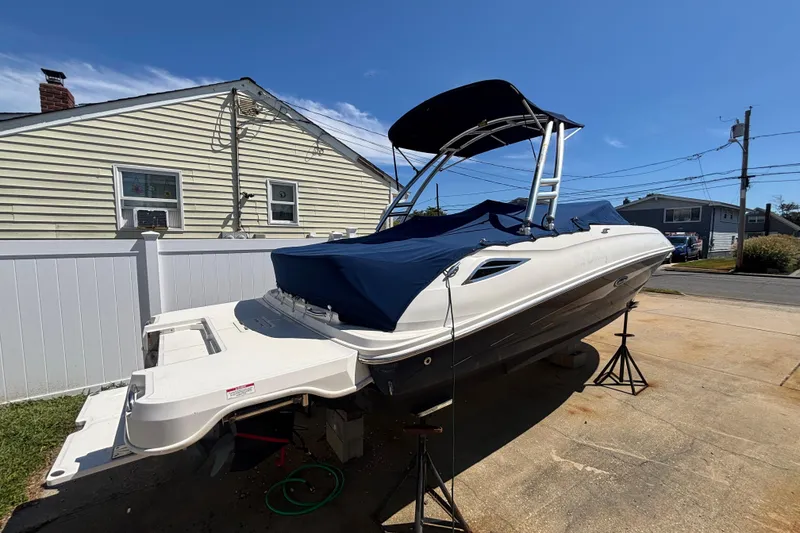 Slide: The Image of 2015 Sea Ray 240 Sundeck boat on stands, covered, in residential driveway. - 36