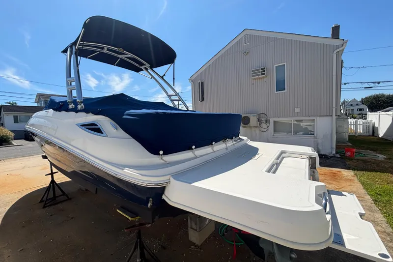 Slide: The Image of 2015 Sea Ray 240 Sundeck boat with blue cover, parked near a house. - 42