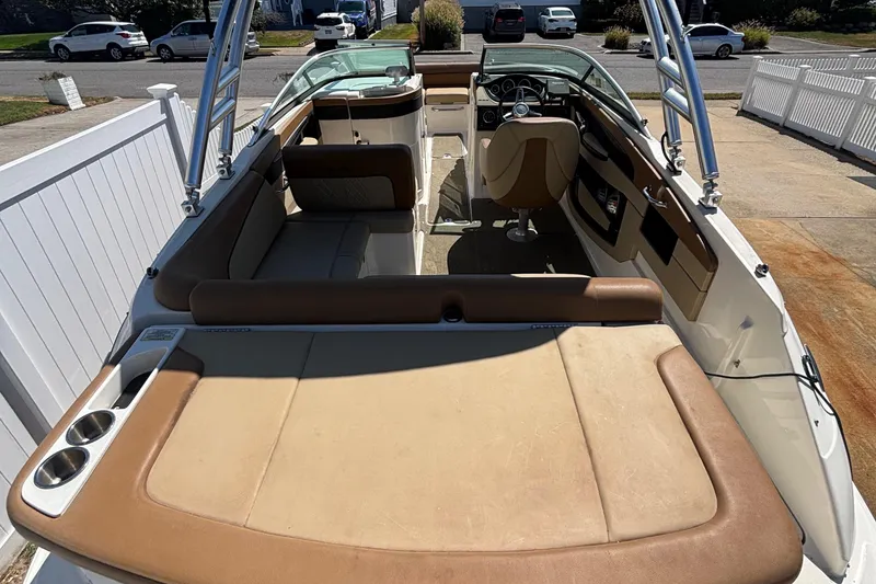 Slide: The Image of 2015 Sea Ray 240 Sundeck interior with seating and steering wheel, parked outdoors. - 7