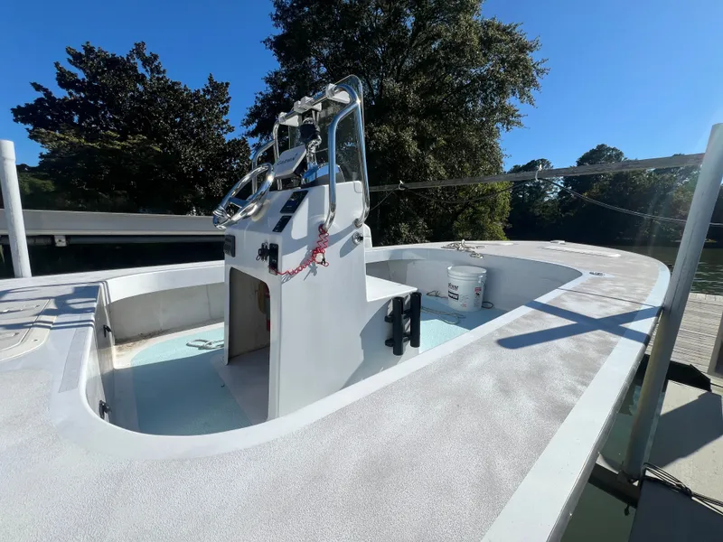 Slide: The Image of Custom 24 boat, 2022 model, docked with clear sky and trees in the background. - 7