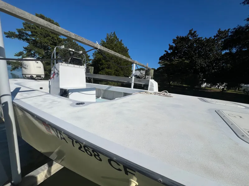 Slide: The Image of Custom 2022 model boat with Suzuki engine, docked near trees under clear blue sky. - 8