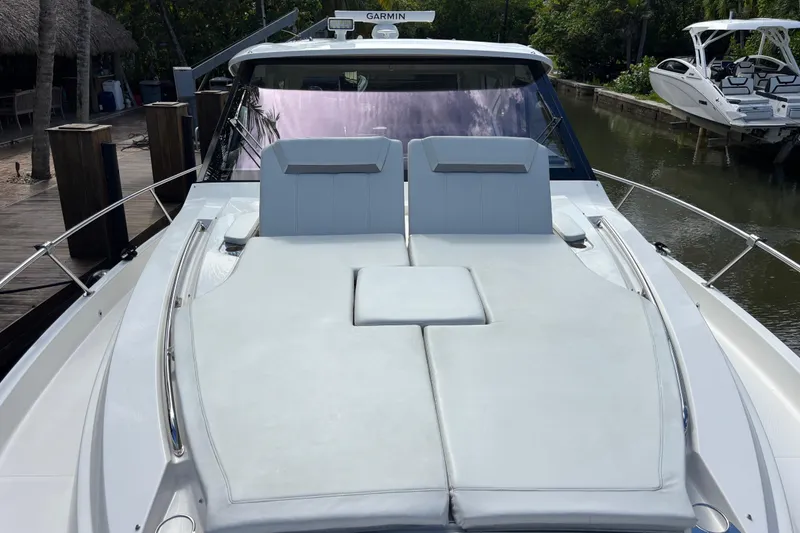 Slide: The Image of 2024 Pursuit OS 445 Offshore boat with triple outboard engines docked in a serene canal. - 12