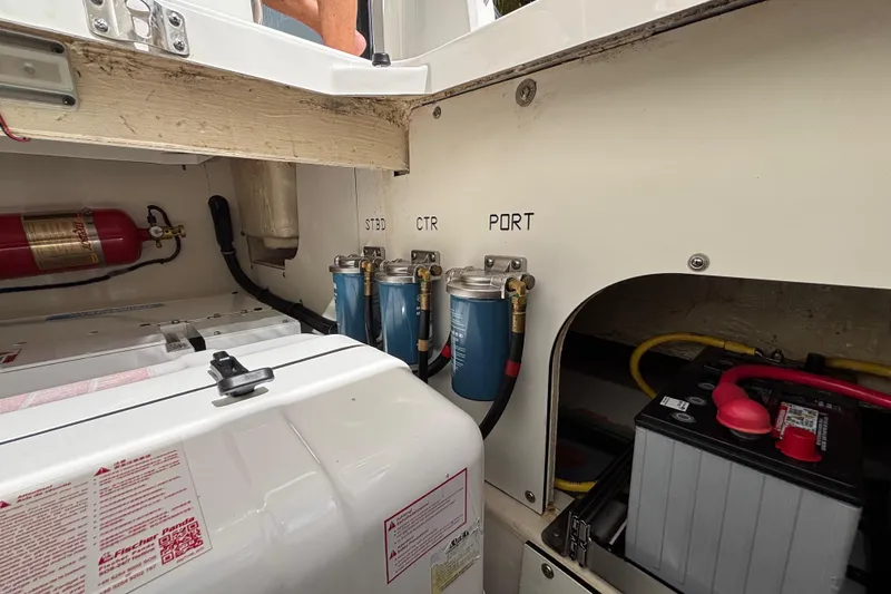 Slide: The Image of 2024 Pursuit OS 445 Offshore engine compartment with filters, battery, and fire extinguisher. - 127