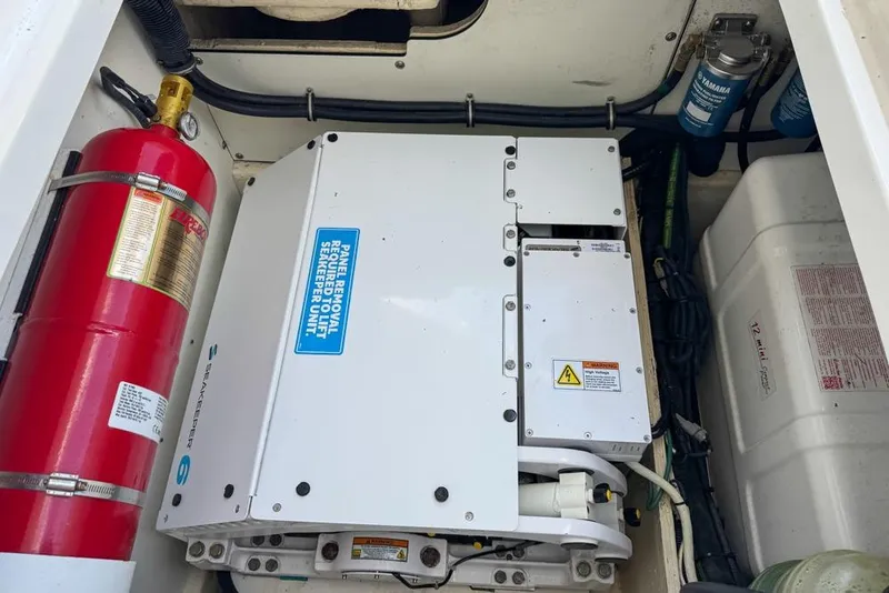 Slide: The Image of 2024 Pursuit OS 445 Offshore engine compartment with Seakeeper unit and fire extinguisher. - 137