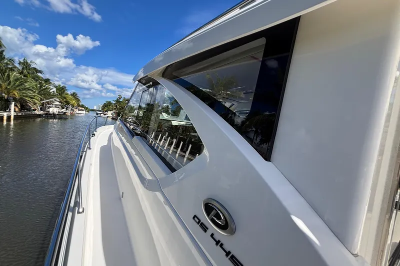 Slide: The Image of 2024 Pursuit OS 445 Offshore boat docked, surrounded by palm trees and clear blue sky. - 24