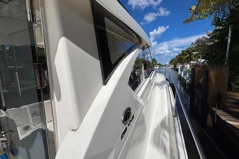 Slide: The Image of 2024 Pursuit OS 445 Offshore boat docked in a scenic canal setting. - 25