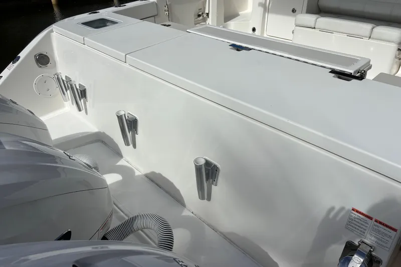 Slide: The Image of 2024 Pursuit OS 445 Offshore boat with triple outboard engines docked in a serene canal. - 43