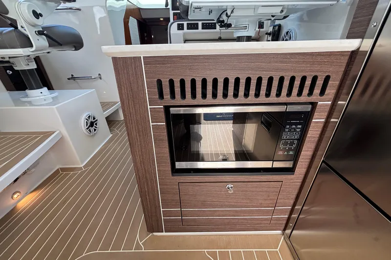 Slide: The Image of 2024 Pursuit OS 445 Offshore boat interior with seating, docked near palm trees. - 50