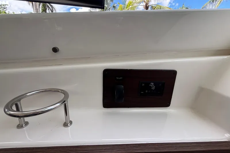 Slide: The Image of 2024 Pursuit OS 445 Offshore boat interior with compass, docked in a scenic canal. - 78