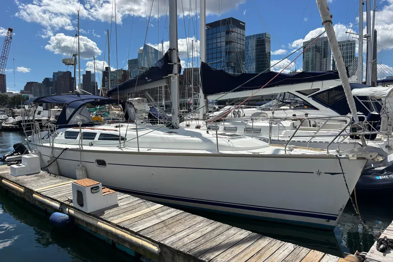 The Image of 2004 Jeanneau Sun Odyssey 40.3 sailboat docked in urban marina with city skyline. - 0