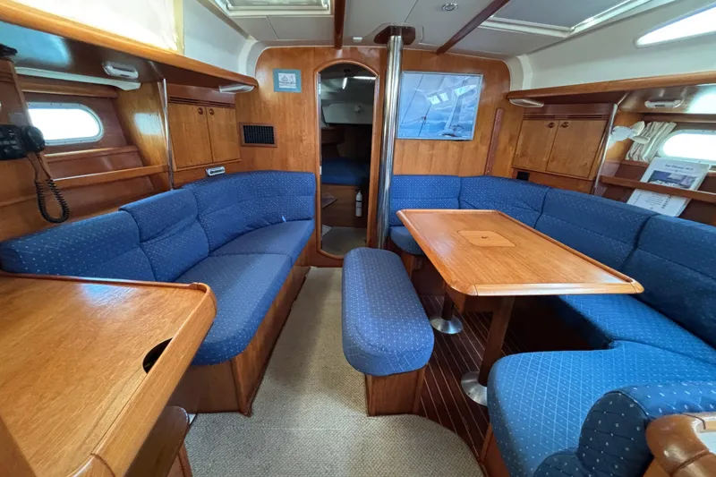 Slide: The Image of Interior of 2004 Jeanneau Sun Odyssey 40.3 sailboat with blue seating and wooden table. - 2