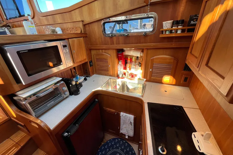 Slide: The Image of 2006 Sabre 36 Flybridge Sedan kitchen with microwave, sink, and wooden cabinetry. - 28
