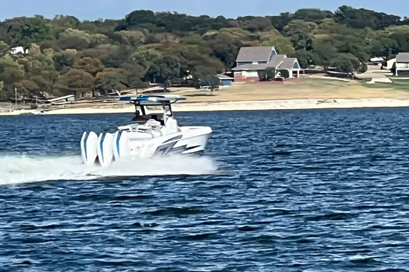Slide: The Image of 2024 Donzi 39 VRZ speedboat cruising on a lake with scenic shoreline backdrop. - 82