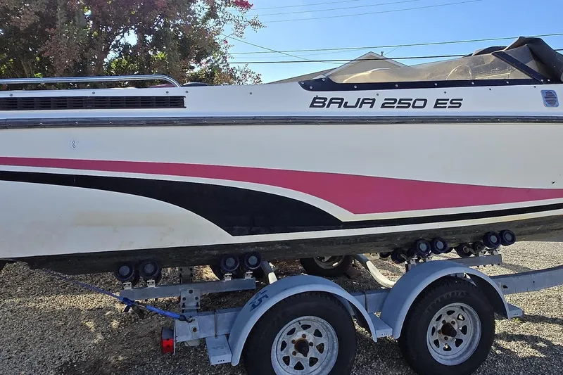Slide: The Image of 1990 Baja 250 ES boat with red and black seating, parked on a sunny street. - 3