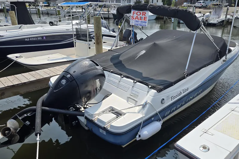 The Image of 2012 Bayliner 190 Bowrider boat docked, covered, with a "For Sale" sign. - 0