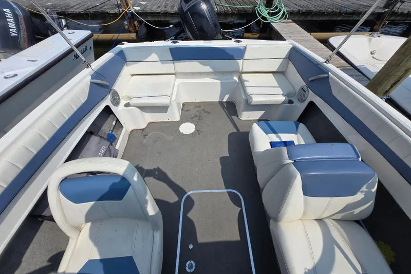 Slide: The Image of 2012 Bayliner 190 Bowrider interior with white and blue seating, docked at marina. - 5
