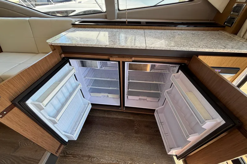 Slide: The Image of Open double-door refrigerator in 2018 Sea Ray Sundancer 460 yacht interior, featuring granite countertop. - 10