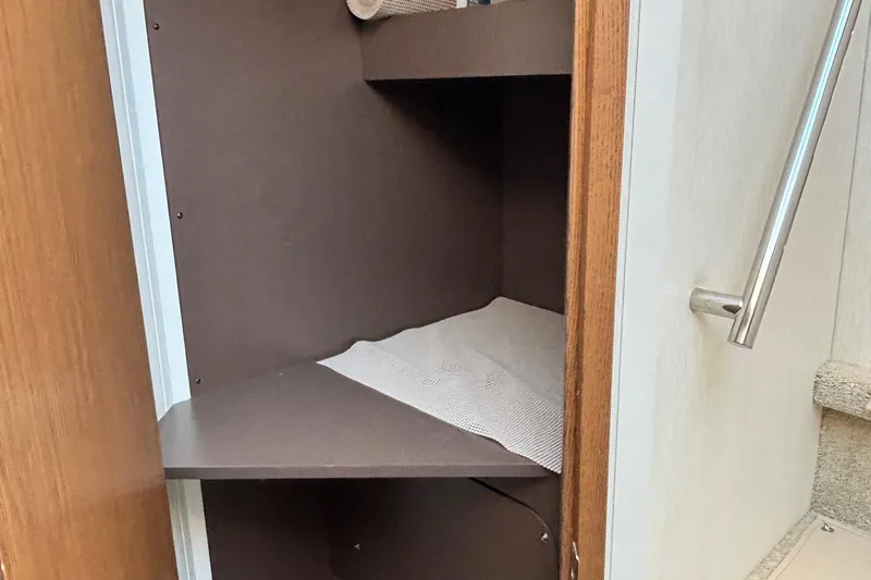 Slide: The Image of Open storage cabinet inside 2018 Sea Ray Sundancer 460 yacht, featuring wooden shelves and metal railing. - 32