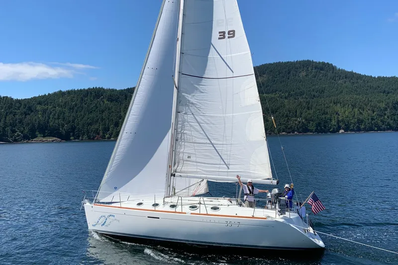 Slide: The Image of Sailing yacht Beneteau First 35s-7, 1994 model, cruising on a scenic lake with forested hills. - 2