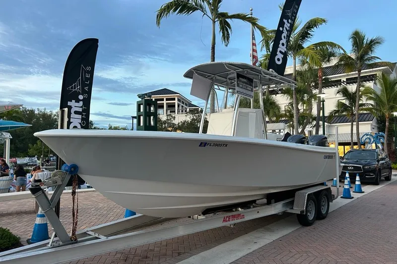 The Image of 2025 Contender 25 Tournament boat on trailer, displayed outdoors with palm trees and banners. - 0
