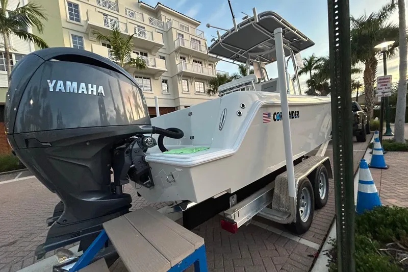 Slide: The Image of 2025 Contender 25 Tournament boat with Yamaha engine on trailer, parked near buildings. - 21