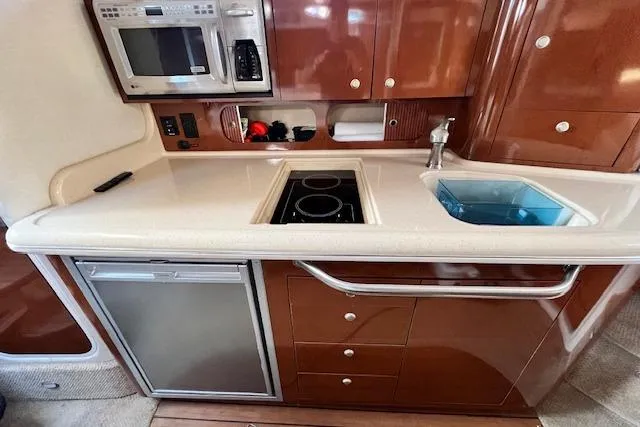 Slide: The Image of 2008 Sea Ray 340 Sundancer kitchen with microwave, stove, sink, and fridge. - 16