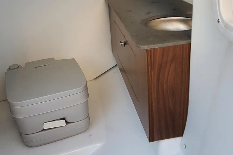 Slide: The Image of 2024 Scarab 285 Wake ID interior with portable toilet and wooden cabinet sink. - 17