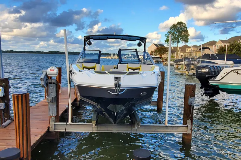 Slide: The Image of 2024 Scarab 285 Wake ID boat docked on a serene lake under a partly cloudy sky. - 33