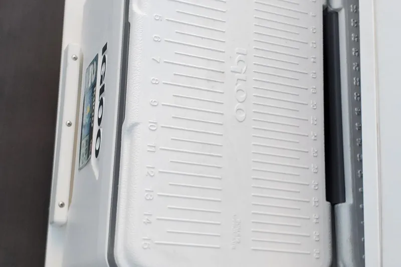 Slide: The Image of White Igloo cooler with measurement markings, featured on a 2024 Scarab 285 Wake ID boat. - 9